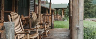 Rustic cabin porch with weathered wooden rocking chairs and a small table on a wooden deck.